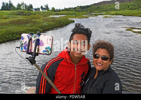 Two people, a couple, of Indian-American descent, take a selfie at Pingvellir National Park in southwestern Iceland. Stock Photo