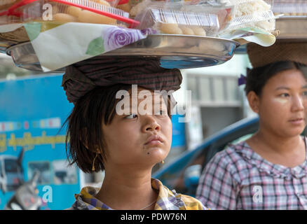 BAGAN, MYANMAR, MAY 16 2018, Woman with basket on her head selling food on street. Stock Photo