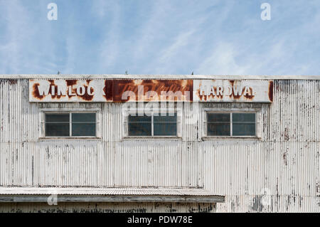 The old deteriorating TrueValue Hardware sign at the top of a corrugated metal building in Winlock, Washington. Stock Photo