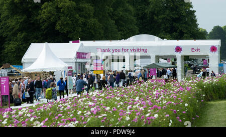 Home time - crowd of people walking towards exit, passing beautiful display of flowering cosmos - RHS Chatsworth Flower Show, Derbyshire, England, UK. Stock Photo
