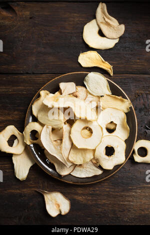 Various fruit chips on dark wooden background, copy space. Assorted dehydrated apple, pear, melon, mango fruit chips - healthy vegan snack. Stock Photo
