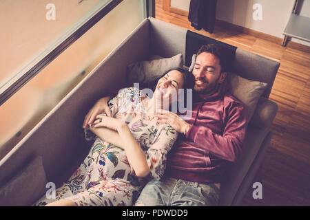 beautiful couple of models lay down on the sofa at home enjoying the lifestyle and relaxing. smile and cheerful people having leisure activity indoor Stock Photo