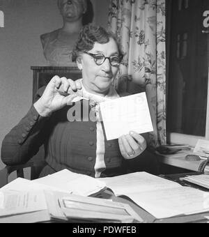 1940s woman with glasses. An older lady is opening an envelope with a letter knife. There are documents and letters on the office desk in front of her. 1942. Photo Kristoffersson/A83-4 Stock Photo