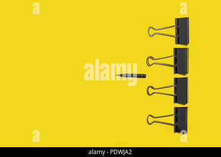 four big paper clips against little pencil Stock Photo