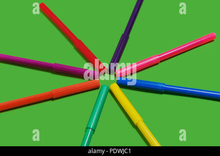 felt pens lying cap to cap on a green background Stock Photo