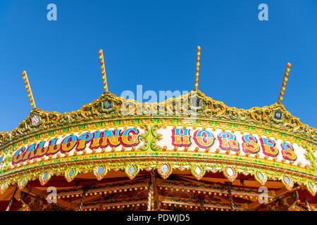 A close up of a coourful galloping horses carousel or roundabout at a funfair in the UK in summer Stock Photo