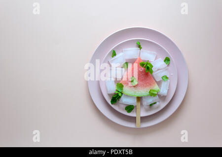 Frozen watermelon popsicles – homemade ice cream with mint on pink plate. Top view Stock Photo