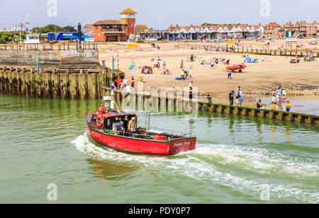 Small red fishing boat entering the River Arun by West Beach, Littlehampton, a small holiday resort on the south coast in West Sussex, UK in summer Stock Photo