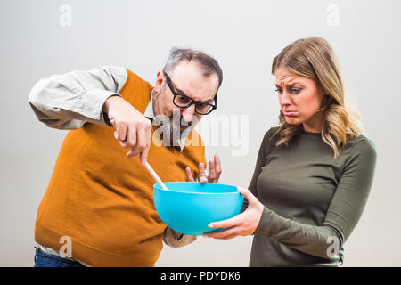Nerdy man would like that his wife spend more time in the kitchen,but she doesn't want to. Stock Photo