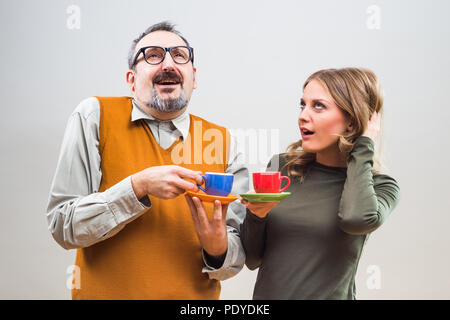 Funny nerdy man and beautiful woman enjoy drinking coffee. Stock Photo