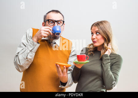 Funny nerdy man and beautiful woman enjoy drinking coffee. Stock Photo