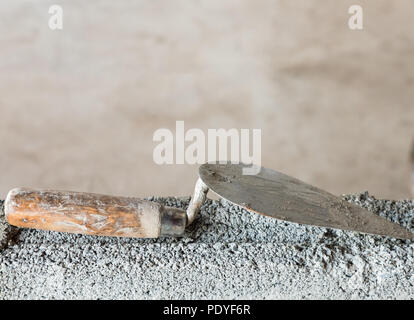 Dirty trowel on the incompleted brick wall in the construction house. Stock Photo