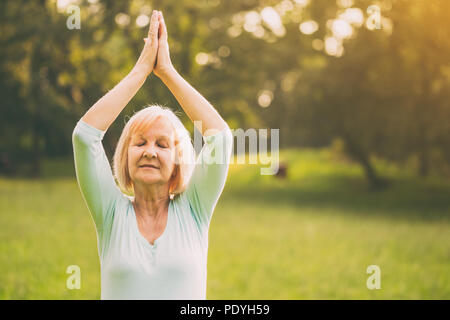 Senior woman enjoys meditating in the nature.Image is intentionally toned. Stock Photo