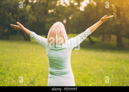 Senior woman enjoys with her arms outstretched in the nature.Image is intentionally toned.