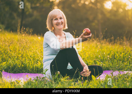 Portrait of active senior woman eating apple after exercise.Image is intentionally toned. Stock Photo