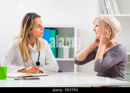 Senior patient telling female doctor how she is having problems with her ears. Stock Photo