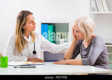 Female doctor consoling her senior patient in office. Stock Photo
