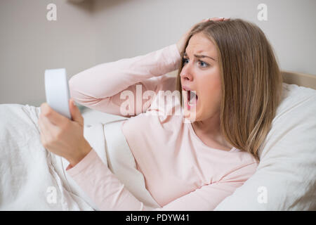 Terrified woman holding alarm clock. Stock Photo