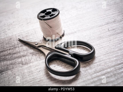 Small Pair Of Scissors Next To A Thread Spool On A Table - Handmade Sewing Concept Stock Photo