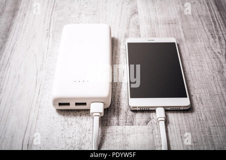 Smartphone On A Table Getting Recharged By A Powerbank, High Angle View Stock Photo
