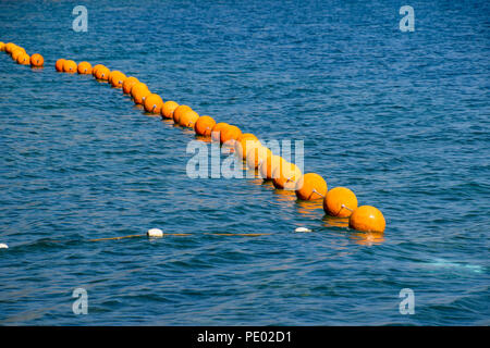 Orange buoys on a rope in the sea. Fencing for swimming in the sea. Stock Photo