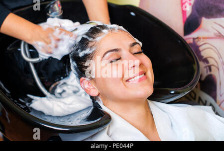 Beautiful young girl enjoying hair washing in hairdressing salon. Stock Photo