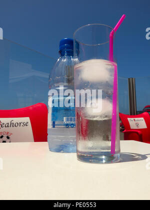 Glass of water with ice outside in sunshine Stock Photo