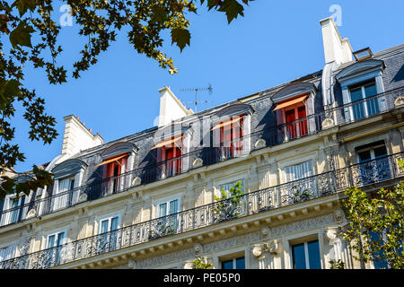 View from down the street of a typical parisian, opulent-looking building of haussmannian style with cut stone facade, carved ornaments and balcony. Stock Photo