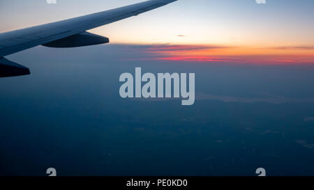 Partial View of Airplane Wing with Colorful Sunrise in the horizon Stock Photo