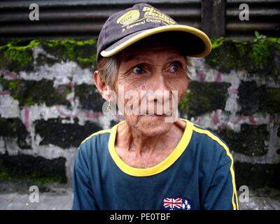 ANTIPOLO CITY, PHILIPPINES: AUGUST 2, 2018: An adult Asian woman sits on a sidewalk and smiles for the camera. Stock Photo