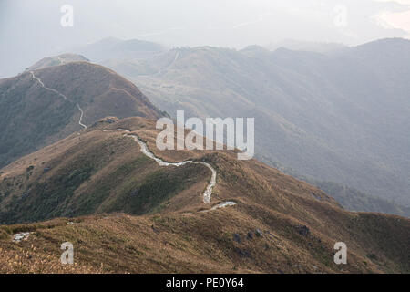 Hiking trail on mountain range from Lantau peak with fog at sunrise in winter, Lantau island, Hong Kong Stock Photo