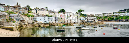 A wide colourful panoramic of a beautiful Cornish seaside harbour village Polruan on the Fowey Estuary. Calm waters and small boats in safe mooring. Stock Photo