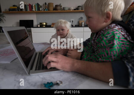Father using laptop with his kids in living room Stock Photo