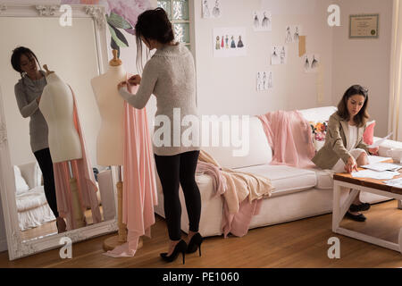 Fashion designer pinning fabric on dressmakers model Stock Photo