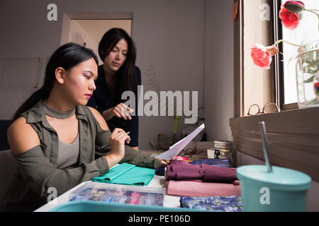 Fashion designers discussing over sketches Stock Photo
