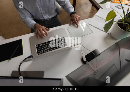 Businessman using glass digital tablet while working on laptop Stock Photo