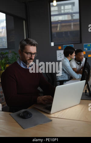 Male executives working over laptop at desk Stock Photo