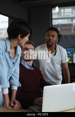 Executives discussing over laptop at desk Stock Photo