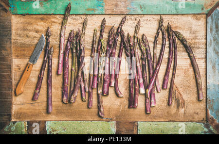 Fresh purple asparagus and knife over wooden tray background Stock Photo