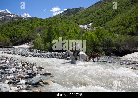 Man on a horse crossing a river in Caucasus mountains in Svaneti, Georgia