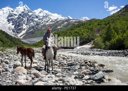 Man on a horse crossing a river in Caucasus mountains in Svaneti, Georgia