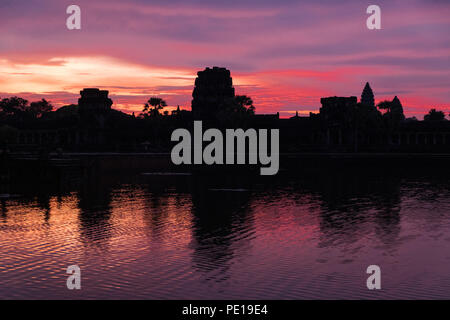 Sunrise over the moat surrounding the temple Angkor Wat - the largest religious monument in the world - near Siem Reap, Cambodia Stock Photo