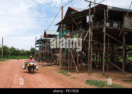 A woman on a loaded up motorcyle in Kampong Phluk, one of Cambodia's 'floating villages' of Tonle Sap, during the dry season. Stock Photo