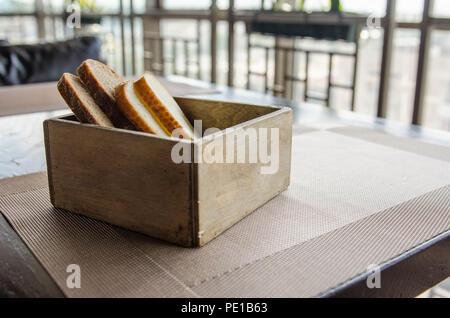 Cut bread in wooden bread box. Four pieces of bread in a beautiful breadbox on a table in a cafe. Fresh cut bread in wooden bread box with background Stock Photo