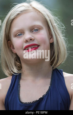 Pretty, young blonde female. preteen,, fashion shoot. Looking  at camera smiling, outside, full frame, blue dress,  model released. Stock Photo