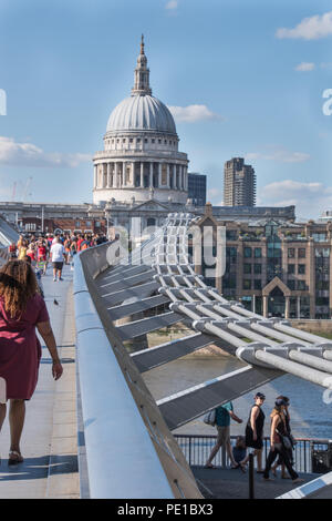 London landmark showing Millennium Bridge and St.Pauls cathedral on a bright sunny day with clear blue sky showing some tourists Stock Photo