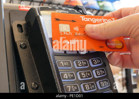 Burnaby, BC, Canada - May 30, 2018 : Close up of woman paying foods and tapping credit card at self-check out counter inside price smart foods store Stock Photo