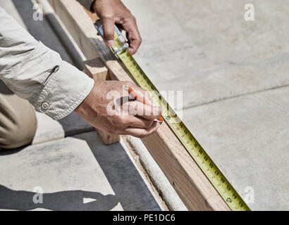 Construction worker using  tape rule to mark a measurement on a cement form board with shallow depth of field Stock Photo