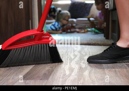 Young woman sweeping, cleaning the floor with O Cedar broom Stock Photo