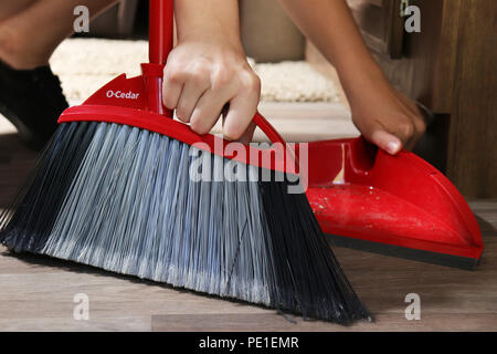 Young woman sweeping, cleaning the floor with O Cedar broom Stock Photo